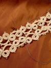 Driftspine Tatted Lace Bracelet on warm fabric backdrop