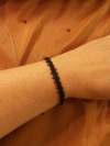Black tatted bracelet shown in rustic, symbolic environment.