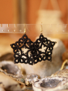 Close-up of black lace stars hanging from display in front of boho background.