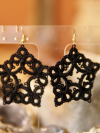 Black tatted earrings shaped like stars resting near geode stones.