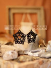 Hand-tatted black star earrings in front of bohemian background
