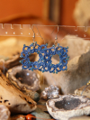 Elegant blue tatted earrings photgraphed with a bohemian background.