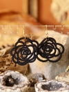 Sub Rosa tatted earrings in black thread displayed in front of boho backdrop