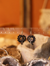 Small tatted lace earrings featuring charms and loops.