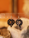 Black lace earrings with silver cross charms on rustic display.
