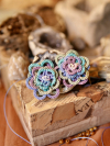 Multi-layered lace flower earrings resting on a rustic surface.