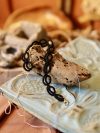 Black tatted lace bracelet named Pulsebound displayed on a driftwood prop.