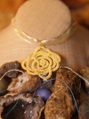 Day's First Bloom Tatted Rose Ribbon Necklace A single spiral lace rose in golden thread lies centered on bohemian background