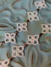 Close up of square lace motifs joined by leopard-spotted glass beads.