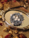 Blue tatted lace cameo brooch on a silver mirror with clay flowers