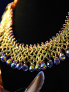 Gold tatted lace necklace with iridescent drops displayed on a black bust