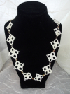 Handmade white tatted lace necklace called Pathwoven displayed on black stand.