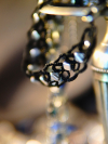 Close-up of black tatted necklace with silver accents on a metal surface.
