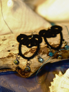 Closeup of black tatted earrings with iridescent beads