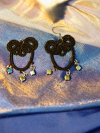 Black tatted earrings on blue-gold fabric backdrop