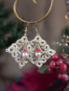 Close-up of delicate lace diamond earrings with red Santa-hat drops and gold hoo