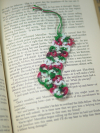 Handmade tatted lace stocking in festive colors used as a holiday bookmark