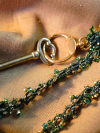 Green tatted lanyard with beads coiled on tan cloth