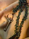 Beaded green lace lanyard beside a key on fabric