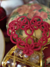 Handmade red tatted heart ornament displayed beside vintage objects.