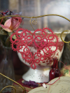 Red tatted lace heart ornament shown on decorative background.