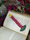 Hand-tatted Christmas candle lace bookmark resting on open vintage book.