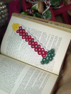 Hand-tatted Christmas candle lace bookmark resting on open vintage book.