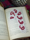 Holiday candy cane bookmark tatted in red and white thread displayed across book