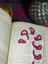 Festive tatted lace candy cane bookmark displayed across vintage book pages in a