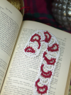 Handmade lace candy cane bookmark arranged on printed book text in a Christmas-t