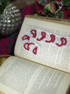 Hand-tatted lace candy cane bookmark in red and white resting on the pages of an