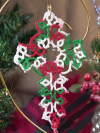 Close-up of a tatted lace cross bookmark in traditional Christmas colors suspend