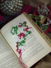 Handmade lace cross bookmark in Christmas colors photographed on the pages of a