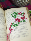 Festive tatted lace cross bookmark displayed on an open book with evergreen and