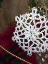 White tatted snowflake ornament in original lace design hanging on display
