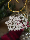 Sparkling silver tatted snowflake earrings shown in winter lighting.