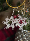 Close-up of tatted snowflake earrings made with silver sparkle thread.