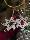 Lightweight tatted lace snowflake earrings photographed near greenery.