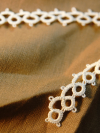 Detail shot of hand tatted lace by the yard displayed on neutral fabric