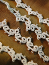 Handmade heirloom tatted lace arranged on neutral linen fabric
