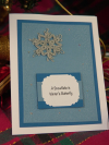 Close-up of tatted lace snowflake card with decorative quote on blue and white c