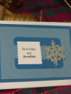 Detail shot of a tatted lace snowflake attached to layered cardstock in icy blue