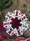 Handmade white lace snowflake ornament shown among festive décor