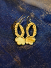 Tatted hemp earrings with star-shaped shell beads on blue fabric.