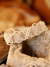 Petalbound tatted lace bracelet resting on natural stone background