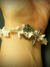White tatted lace bracelet shown on a wrist closes with toggle clasp