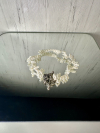 White tatted lace bracelet displayed on a mirror.