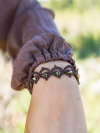 Hand wearing autumn-toned lace bracelet in natural light