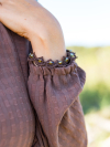 Brown bracelet with crystal accents resting on a sleeve