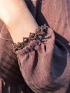Brown tatted lace bracelet with golden crystals on a wrist outdoors